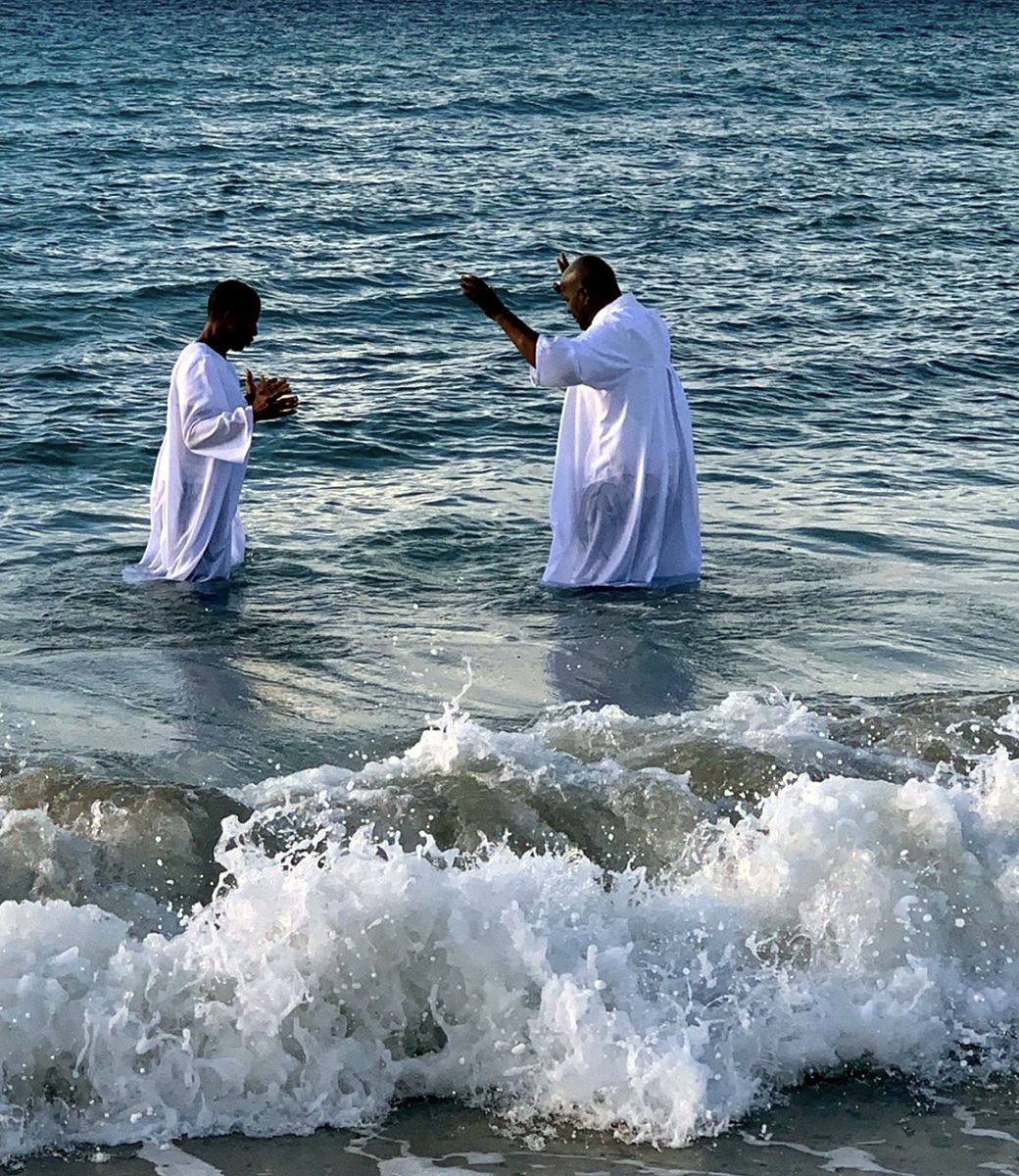 El pastor bautizando a un hermano entre las olas